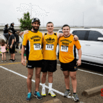 Three 5k runners posing in front of a white truck before the run.